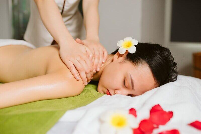 Một người phụ nữ đang nằm thư giãn trên bàn massage với bàn tay dịu dàng đặt trên bụng, cảm giác an toàn và kết nối sâu