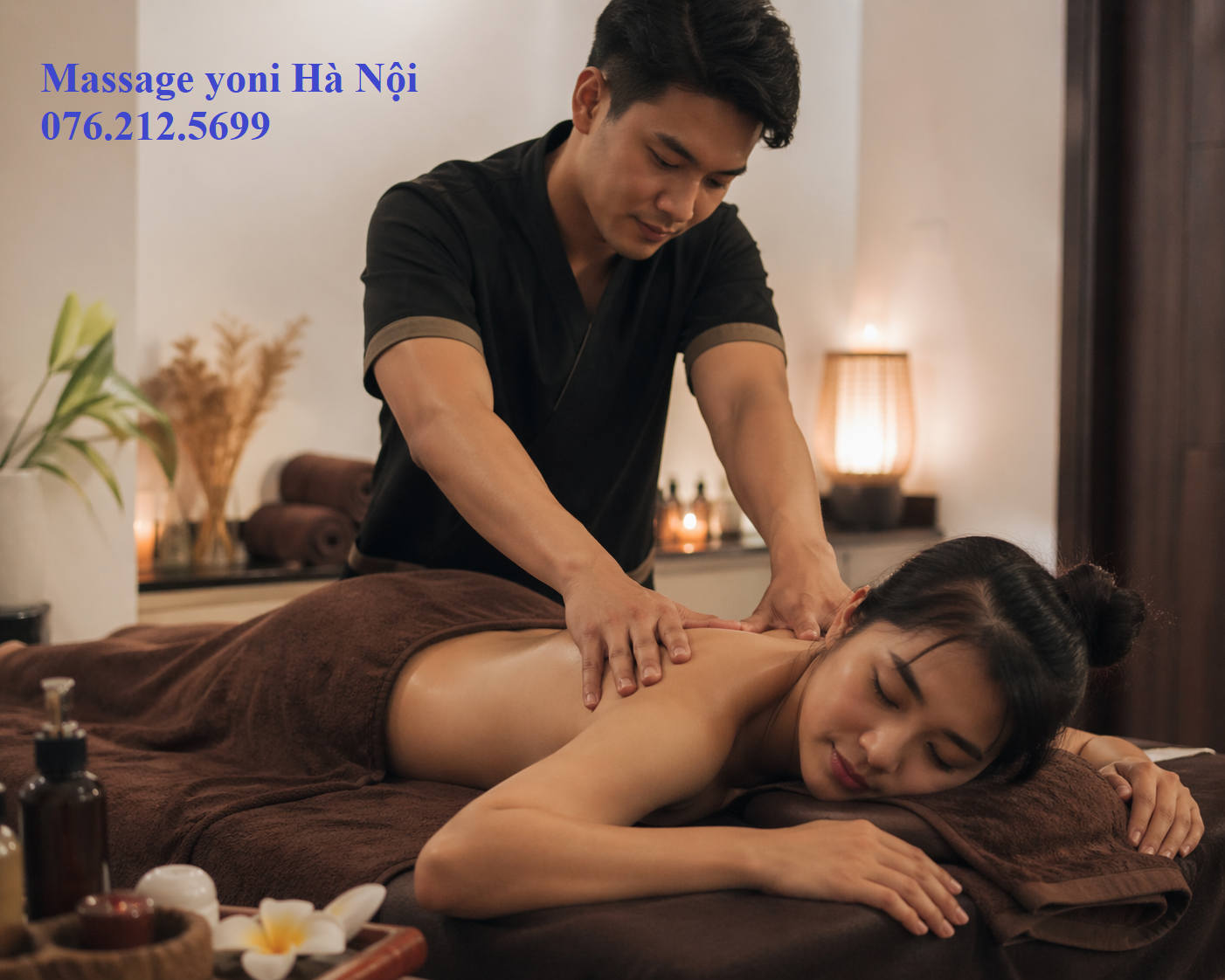 Một phòng trị liệu massage yoni khép kín với ánh sáng nến ấm cúng, rèm cửa dày và những bông hoa tươi trên bàn