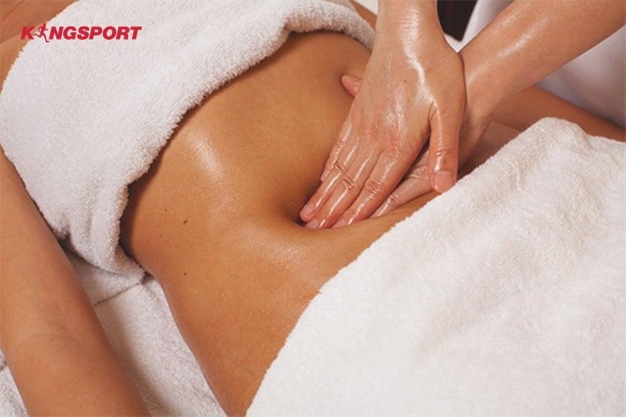 Kỹ thuật viên sử dụng tinh dầu massage vùng bụng với động tác nhẹ nhàng, chính xác theo quy trình trị liệu