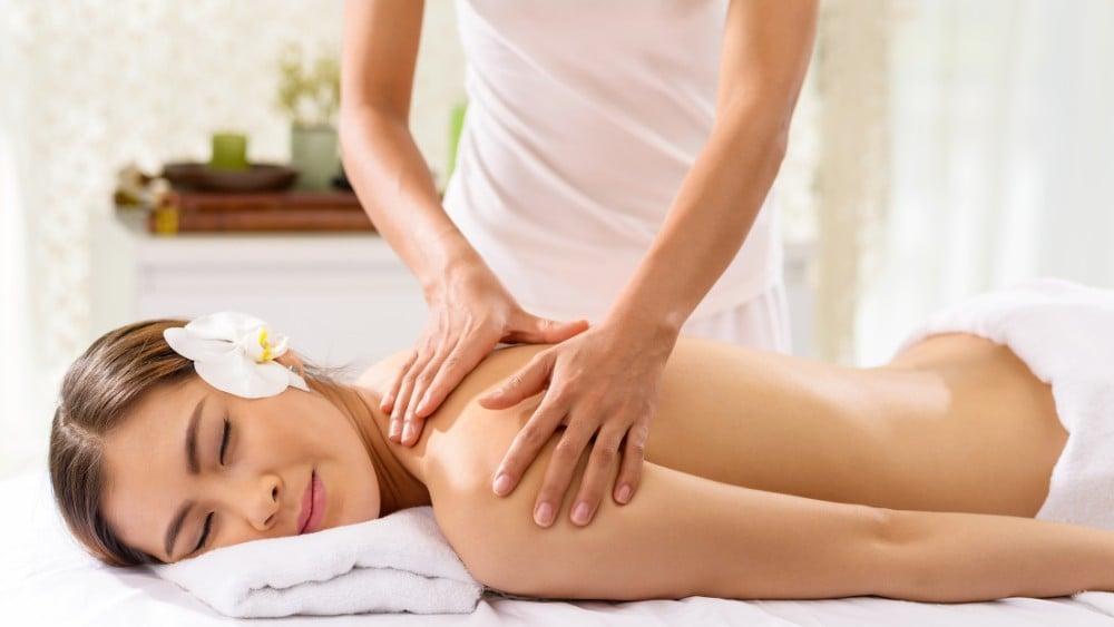 Kỹ thuật viên nữ nhẹ nhàng thực hiện động tác massage vùng lưng dưới, khai thông năng lượng cho khách hàng solo