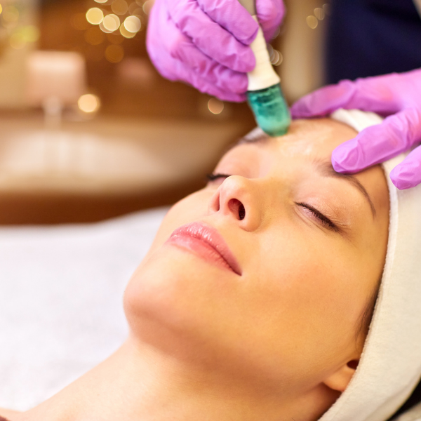 Kỹ thuật viên chuẩn bị dụng cụ và tinh dầu massage yoni Kỹ thuật viên nữ đeo găng tay y tế chuẩn bị tinh dầu cho buổi massage yoni tại spa