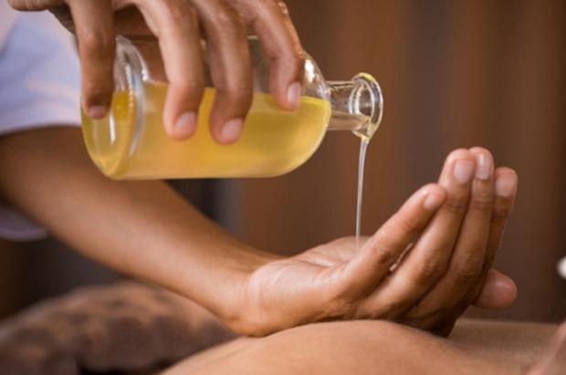 Góc massage trị liệu với đá bazan xếp trên khăn, tinh dầu và hoa khô trong phòng spa nhẹ nhàng
