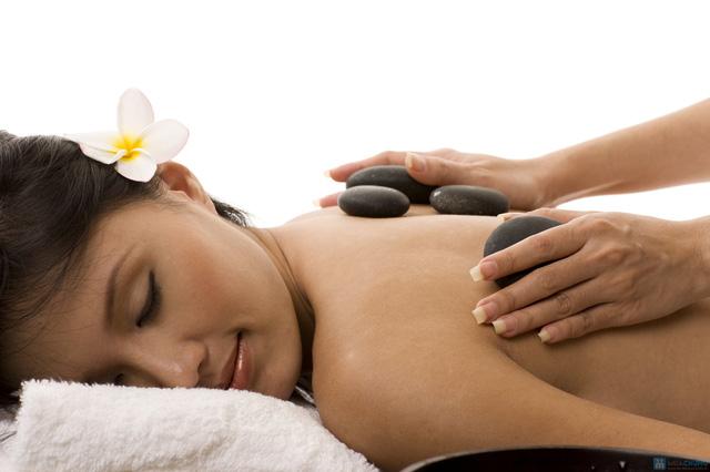 Kỹ thuật viên đang chườm đá nóng bazan dọc sống lưng trong gói Yoni Năng Lượng Độc Bản, tạo cảm giác ấm áp và thư giãn sâu