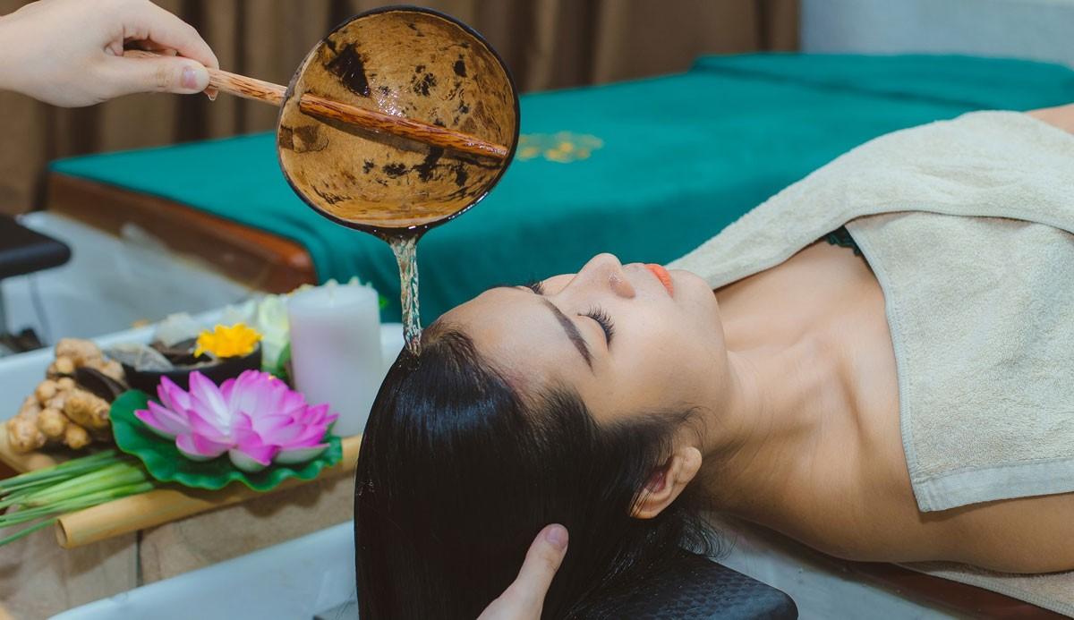 Nữ sinh viên đang thư giãn trên bàn massage với tinh dầu và hoa tươi, không gian nhẹ nhàng giúp giải tỏa áp lực học hành