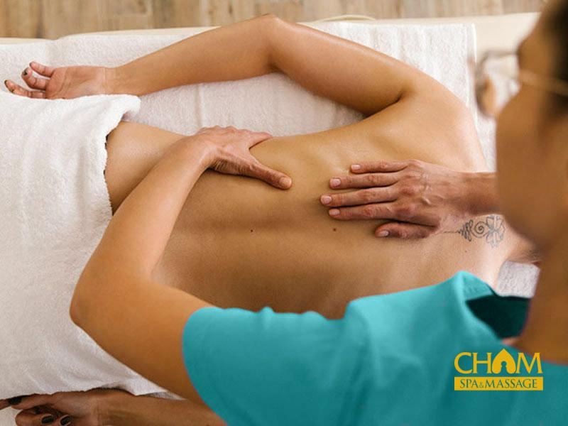Kỹ thuật viên nữ massage vùng chậu nhẹ nhàng cho một phụ nữ trong không gian riêng tư, tối màu, giúp giải tỏa căng thẳng sau ca đêm