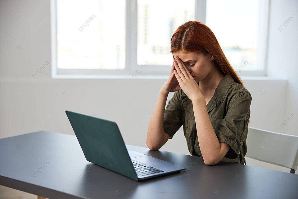 Một phụ nữ văn phòng đang ngồi tựa đầu lên tay, vẻ mặt suy tư và mệt mỏi trước màn hình máy tính với nhiều cửa sổ làm việc