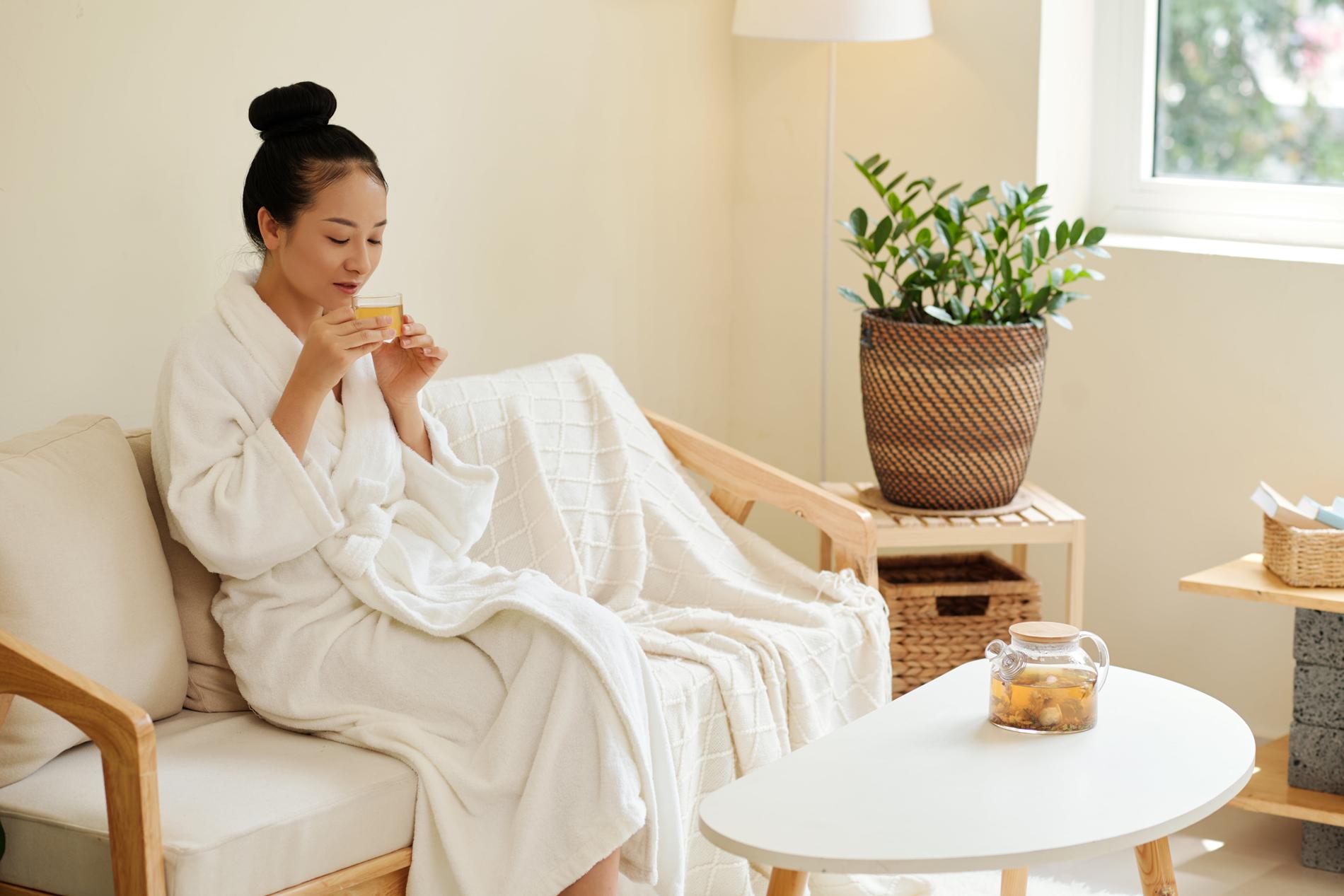 Khách hàng thư giãn với trà thảo mộc và trái cây sau liệu trình massage yoni, không gian ấm cúng và an lành