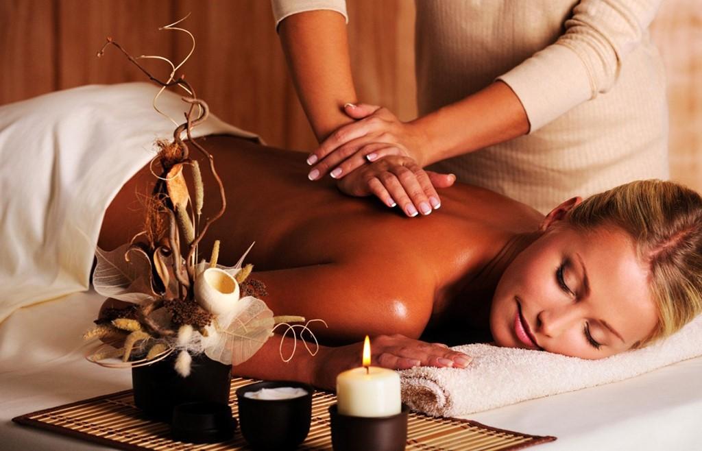 Người phụ nữ đang thư giãn trong không gian trị liệu chuyên nghiệp với tinh dầu thiên nhiên, tập trung vào vùng bụng dưới và hơi thở.