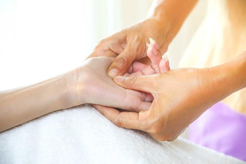 Bàn tay chuyên gia thực hiện động tác massage tinh dầu nhẹ nhàng vùng bụng dưới