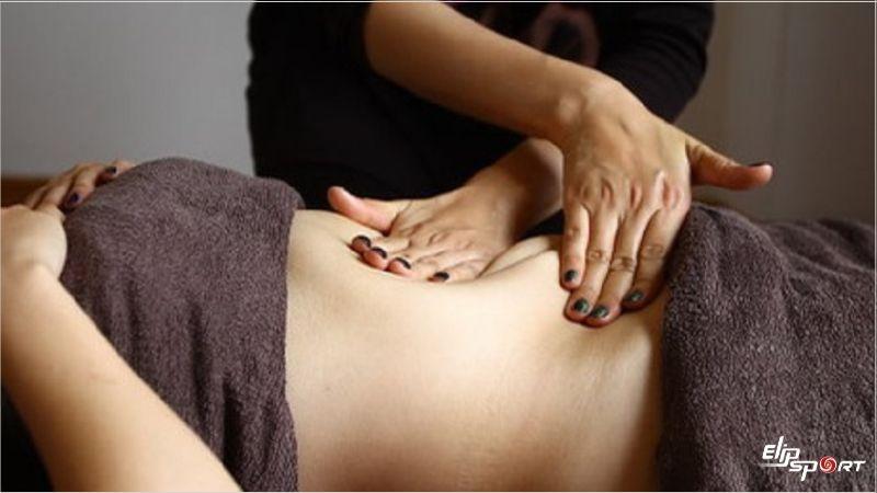 Đôi tay chuyên viên massage nhẹ nhàng vùng bụng dưới cho phụ nữ sau sinh, kết hợp với hướng dẫn bài tập kegel tại giường