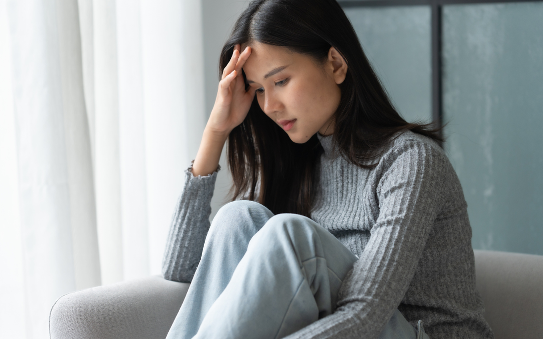 Người phụ nữ ngồi một mình với vẻ mặt buồn bã, phản ánh nỗi tự ti về vùng kín